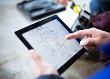 technician holds tablet with mechanical drawing